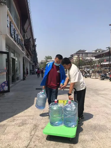 一桶水滑了出去,西安(右)和同事(左)一起把水摆正